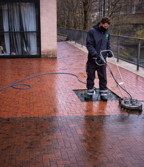 Worker cleaning red brick patio
